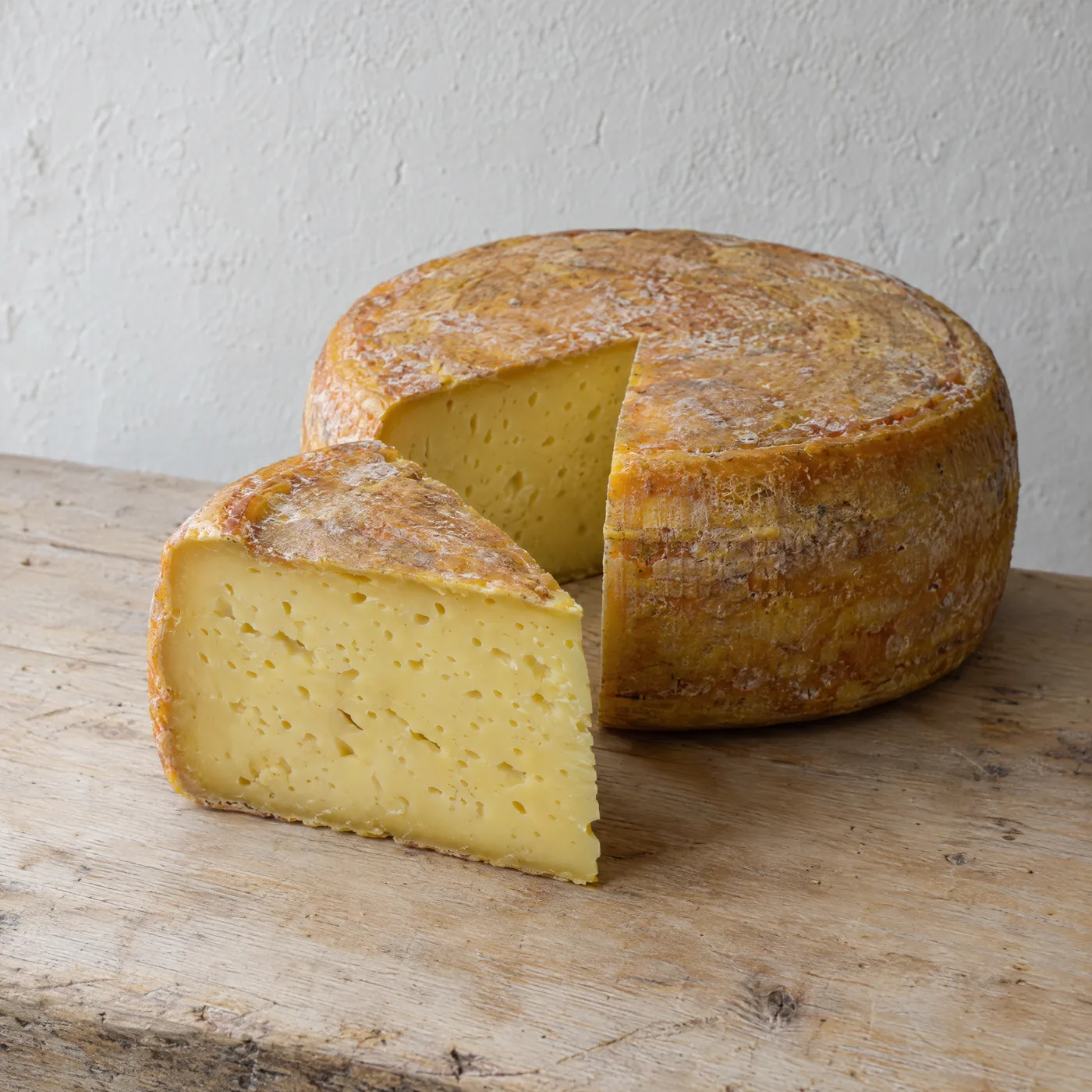Angeschnittener Schnittkäse mit goldener Rinde, buttergelber Teig mit vielen kleinen Löchern