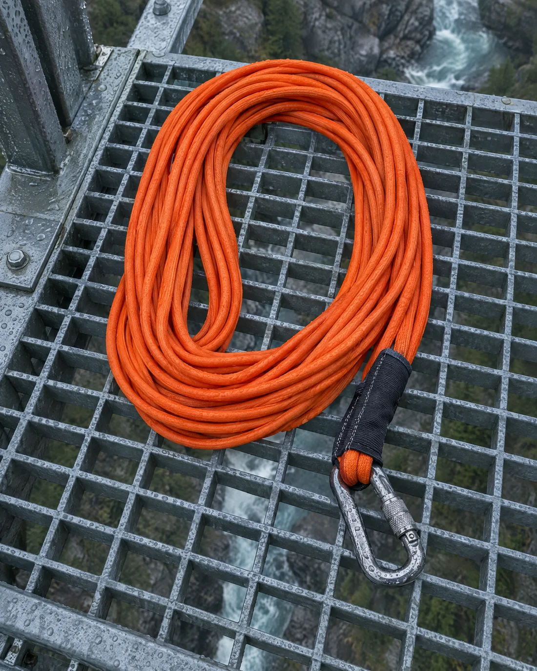 Ein orangefarbenes Bungee-Seil liegt in Schlaufen auf dem Gitterrost der Brücke