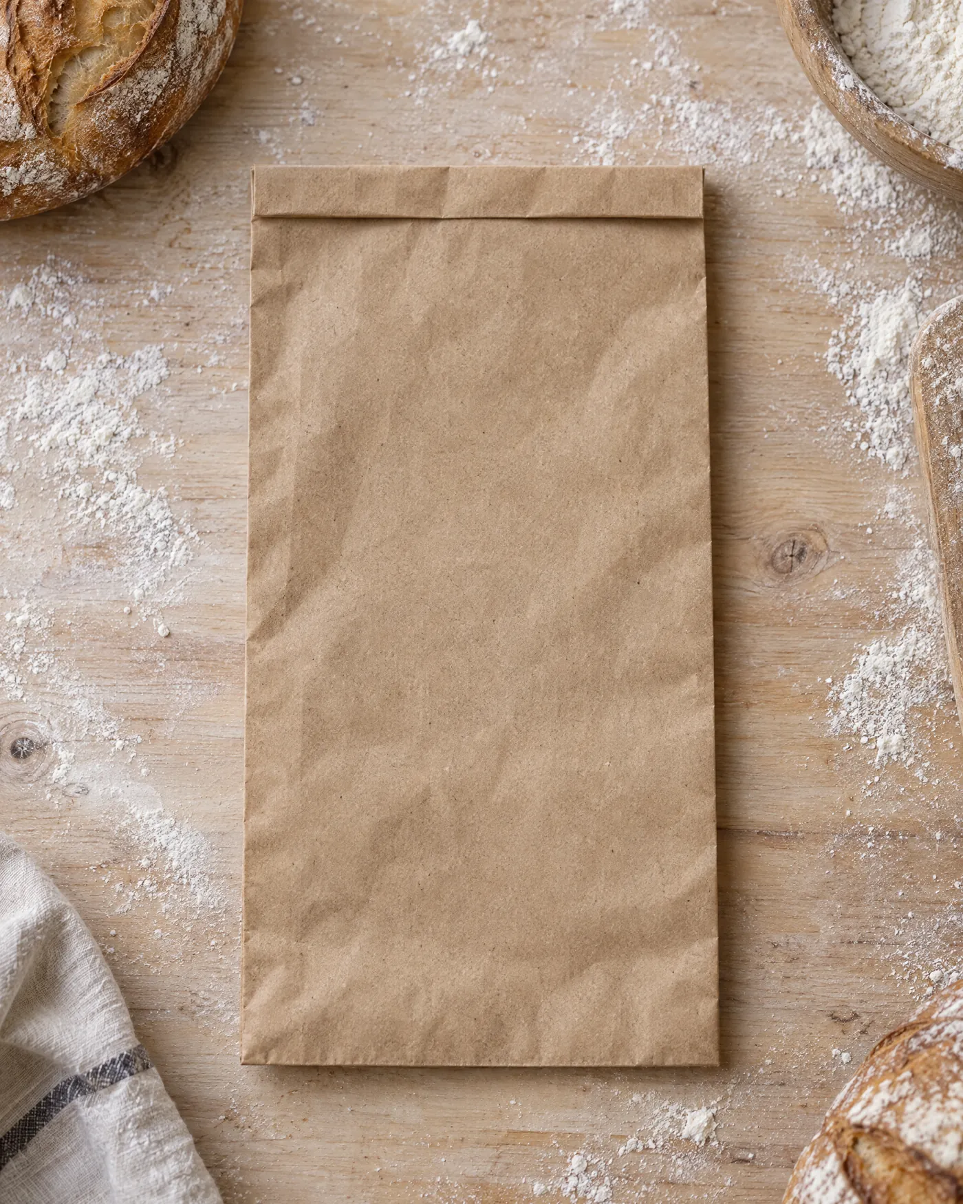 Leere Brottüte aus Kraftpapier, flach von oben auf einem bemehlten Holzbrett